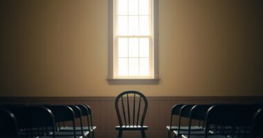 Quiet community hall stage with a single chair representing introverts preparing to speak publicly