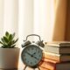 Alarm clock and books on a dresser representing morning self-discipline routine